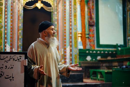 Free Elderly man with a beard, wearing traditional attire, at a colorful temple, expressing thoughtfully. Stock Photo
