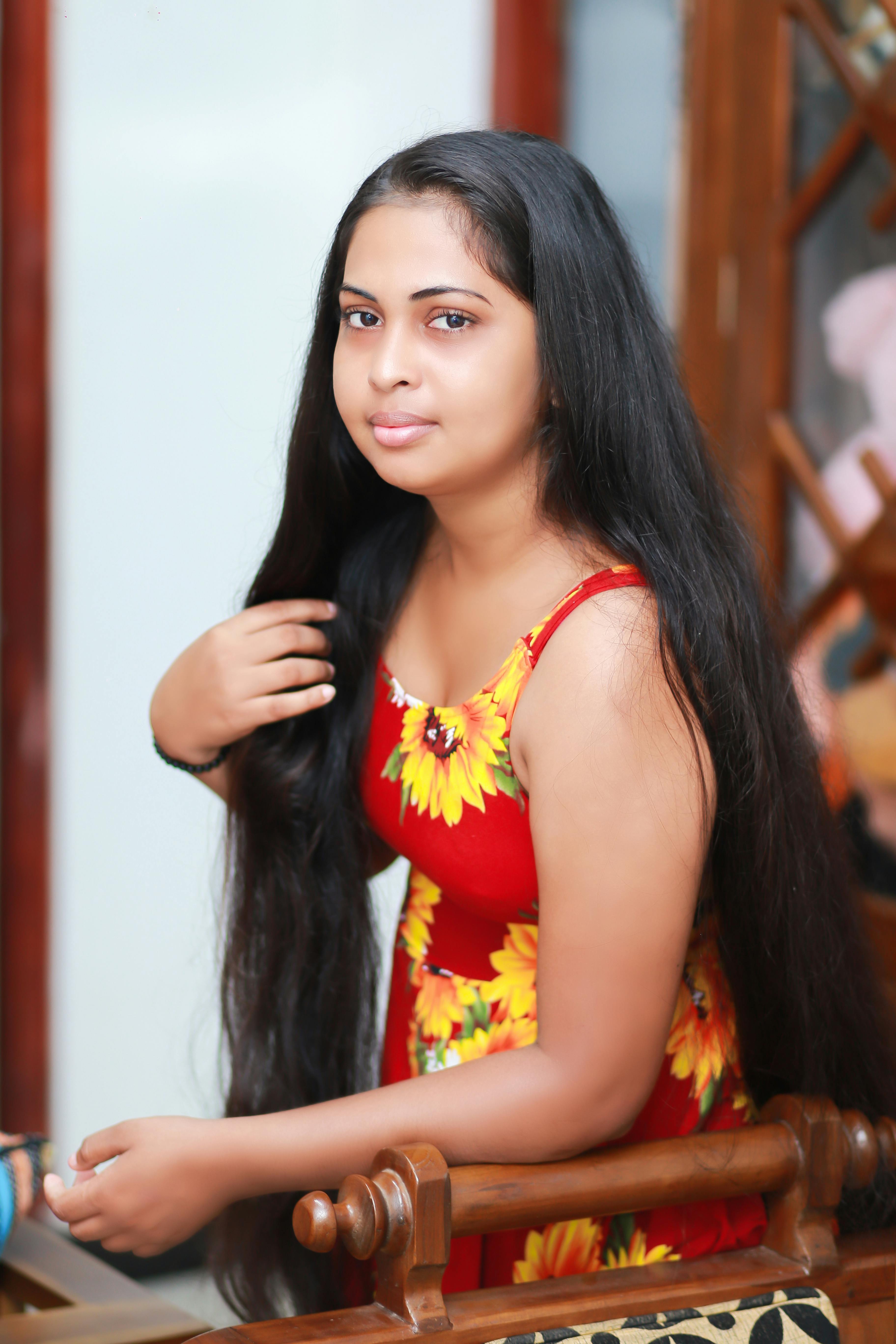 Portrait of a young woman with long hair in a floral print dress posing indoors.