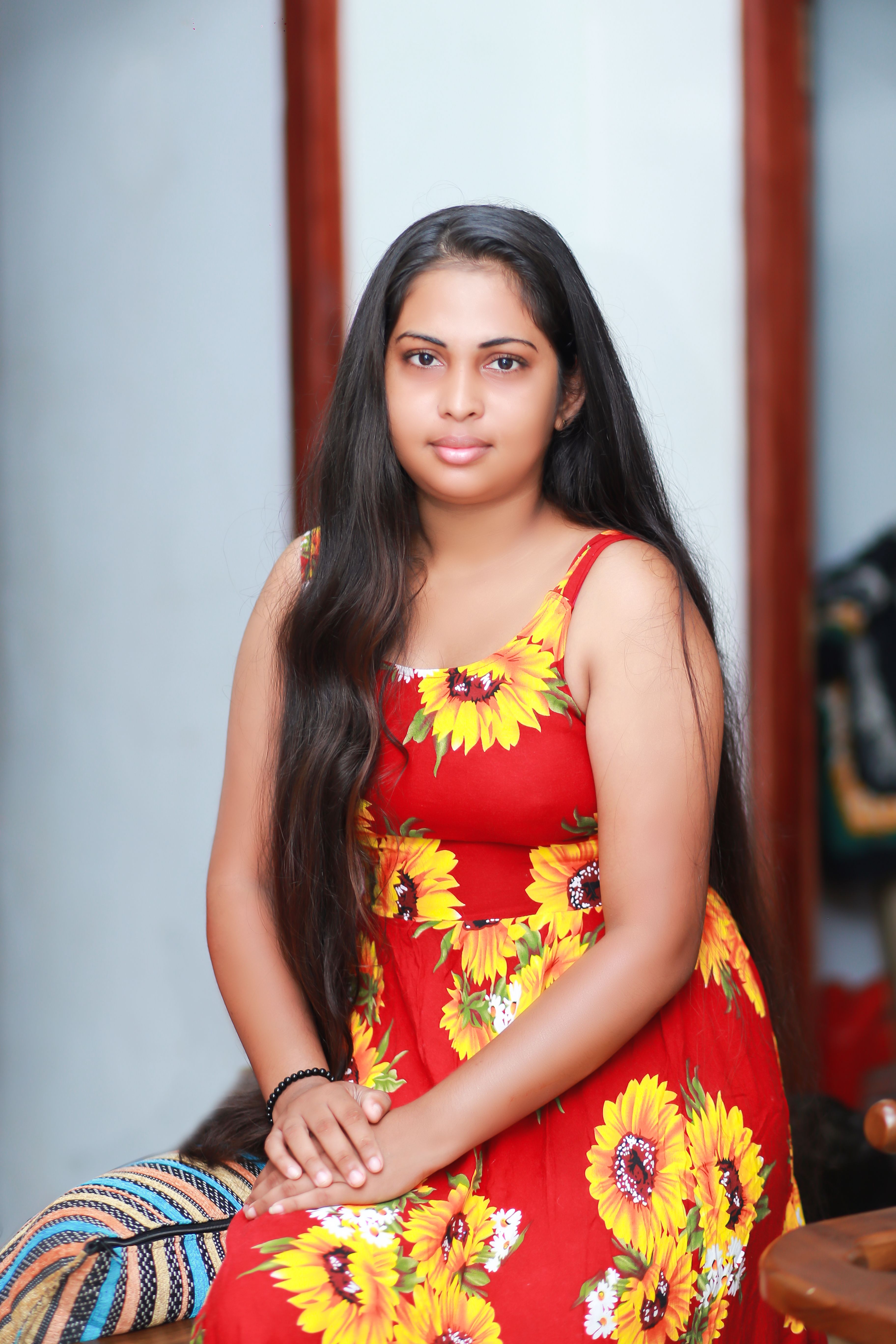 Elegant portrait of a woman wearing a vibrant red floral dress indoors.