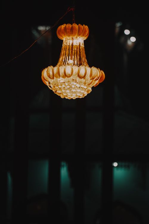 Free An ornate chandelier illuminating a dark room with a warm glow. Stock Photo