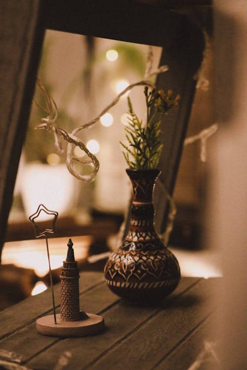 A Brown Ceramic Vase with Plant on a Wooden Table