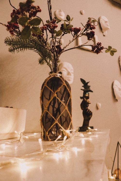 Free Warm, cozy interior featuring a decorated glass vase with flowers and ambient fairy lights. Stock Photo