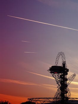 现代钢结构的剪影映衬着充满活力的日落天空，留下可见的痕迹