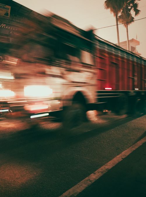 Free A blurred truck speeds through a city street at twilight, capturing dynamic movement and urban energy. Stock Photo