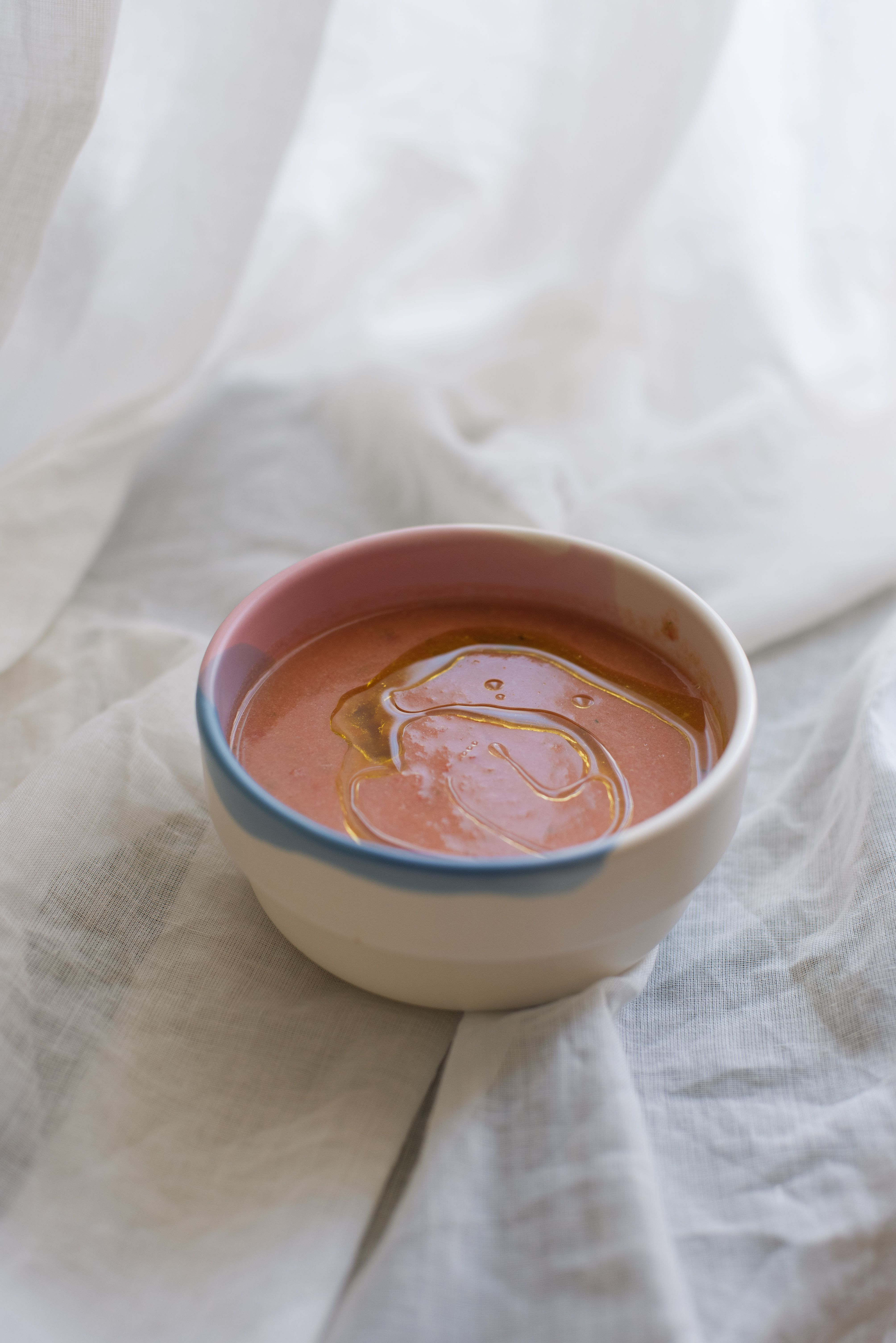 A close-up of a ceramic bowl filled with creamy soup, featuring a soft light and elegant fabric background.