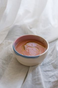 A close-up of a ceramic bowl filled with creamy soup, featuring a soft light and elegant fabric background.