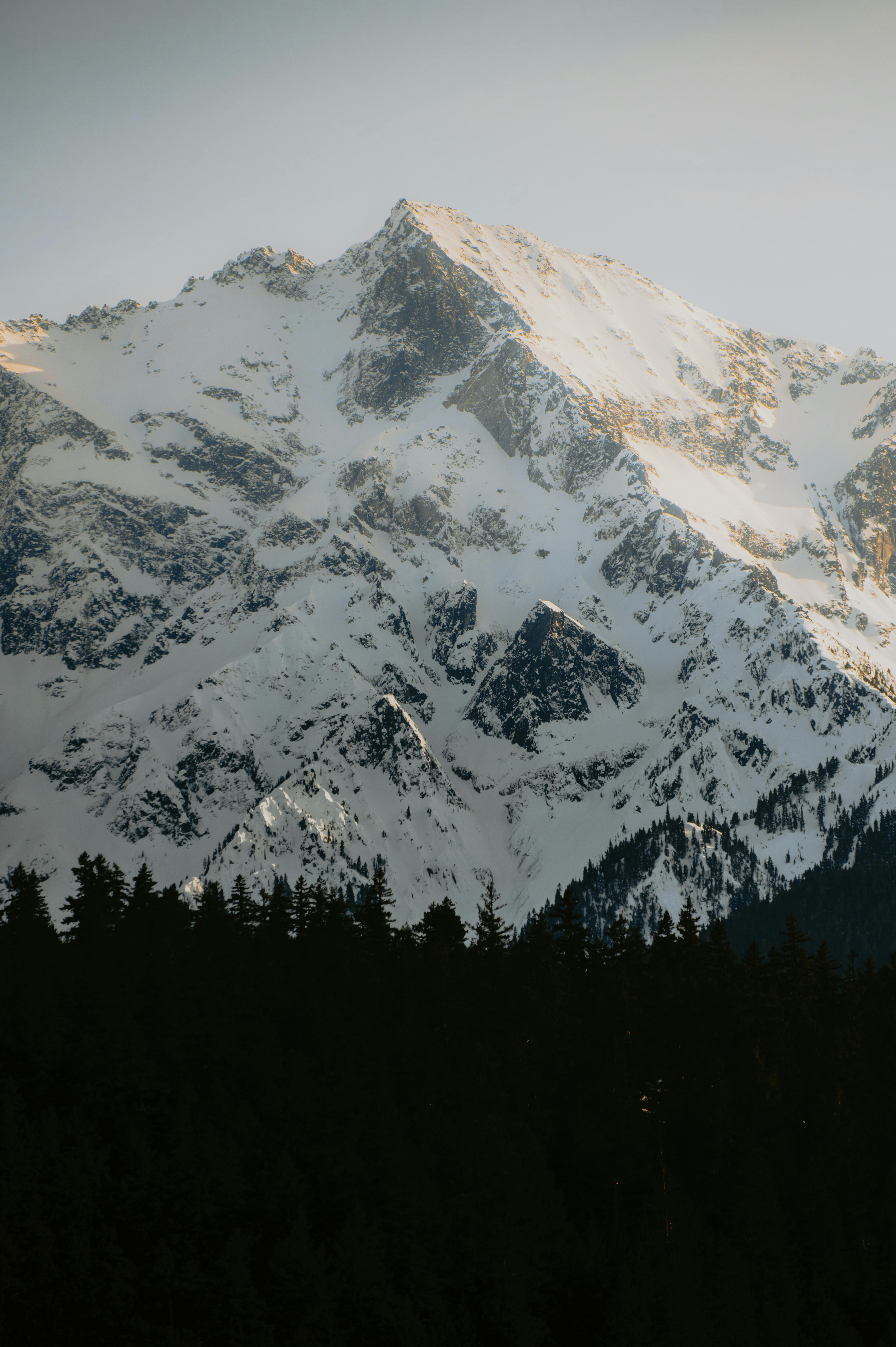 A breathtaking view of a snow-capped mountain peak against a clear sky during dusk, highlighting nature's beauty.