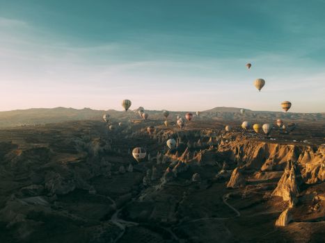 Stunning drone shot of hot air balloons floating over the unique rock formations of Cappadocia, Turkey.