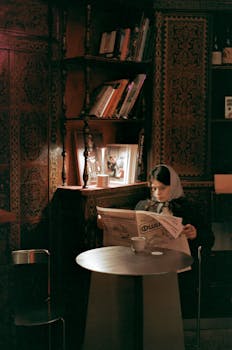 Young woman reads a newspaper in a charming Yerevan café, surrounded by warm, cozy decor.