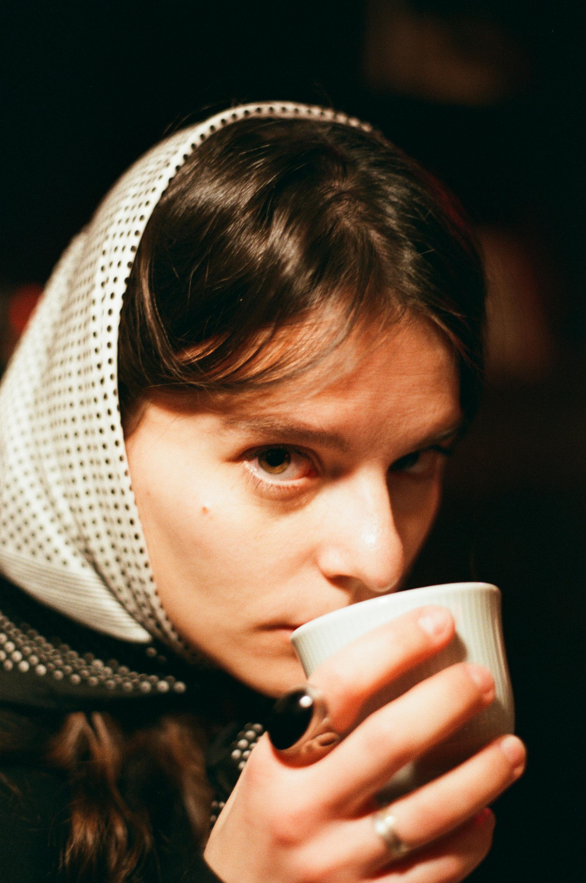 Close-up of a woman sipping tea in a warm, cozy setting.