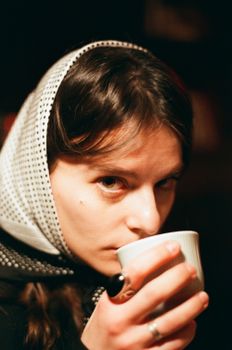 Close-up of a woman sipping tea in a warm, cozy setting.