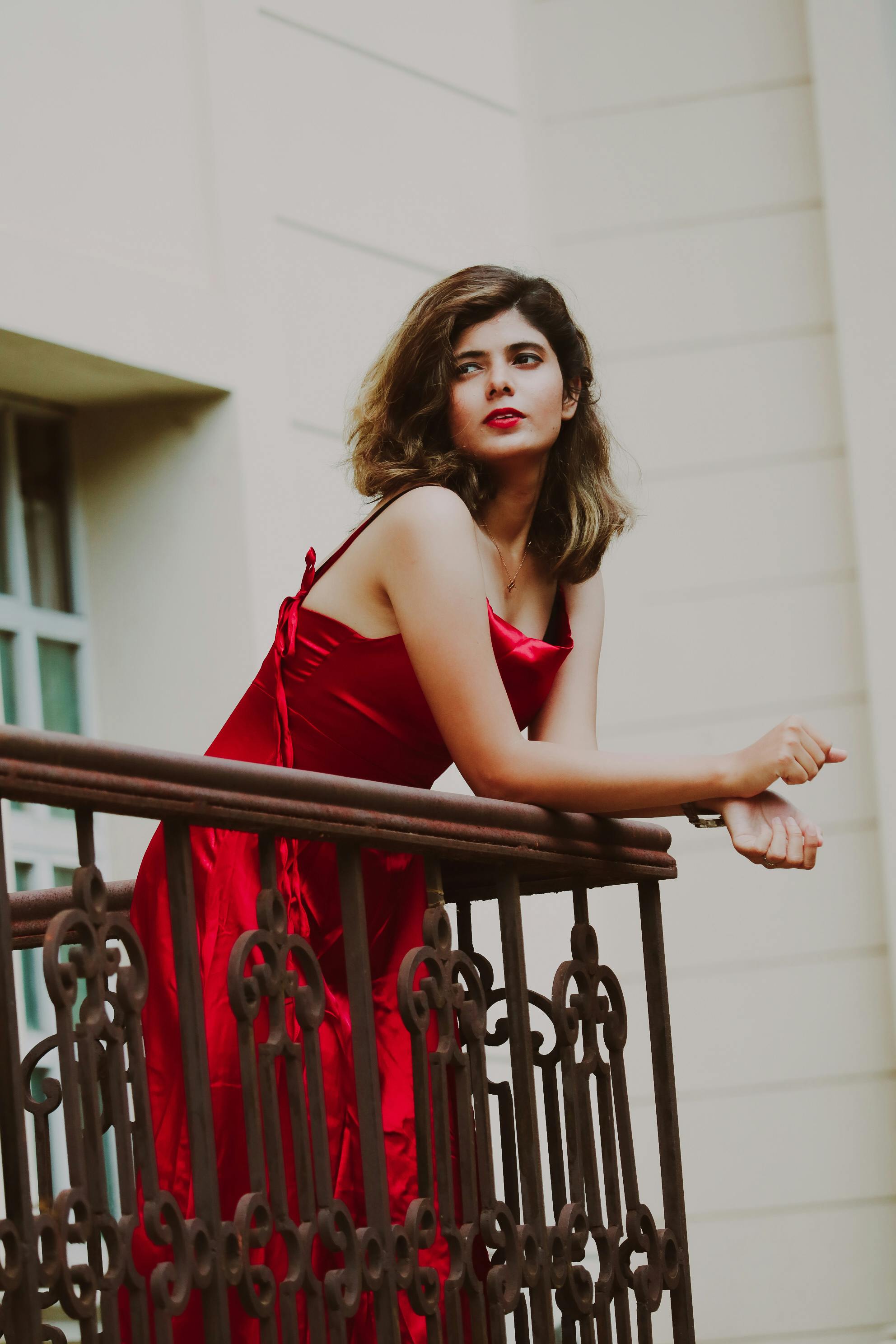 a woman in red spaghetti dress standing on the balcony