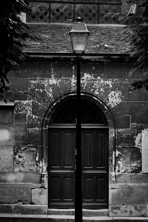 Grayscale Photo of a Street Lamp Near a Door