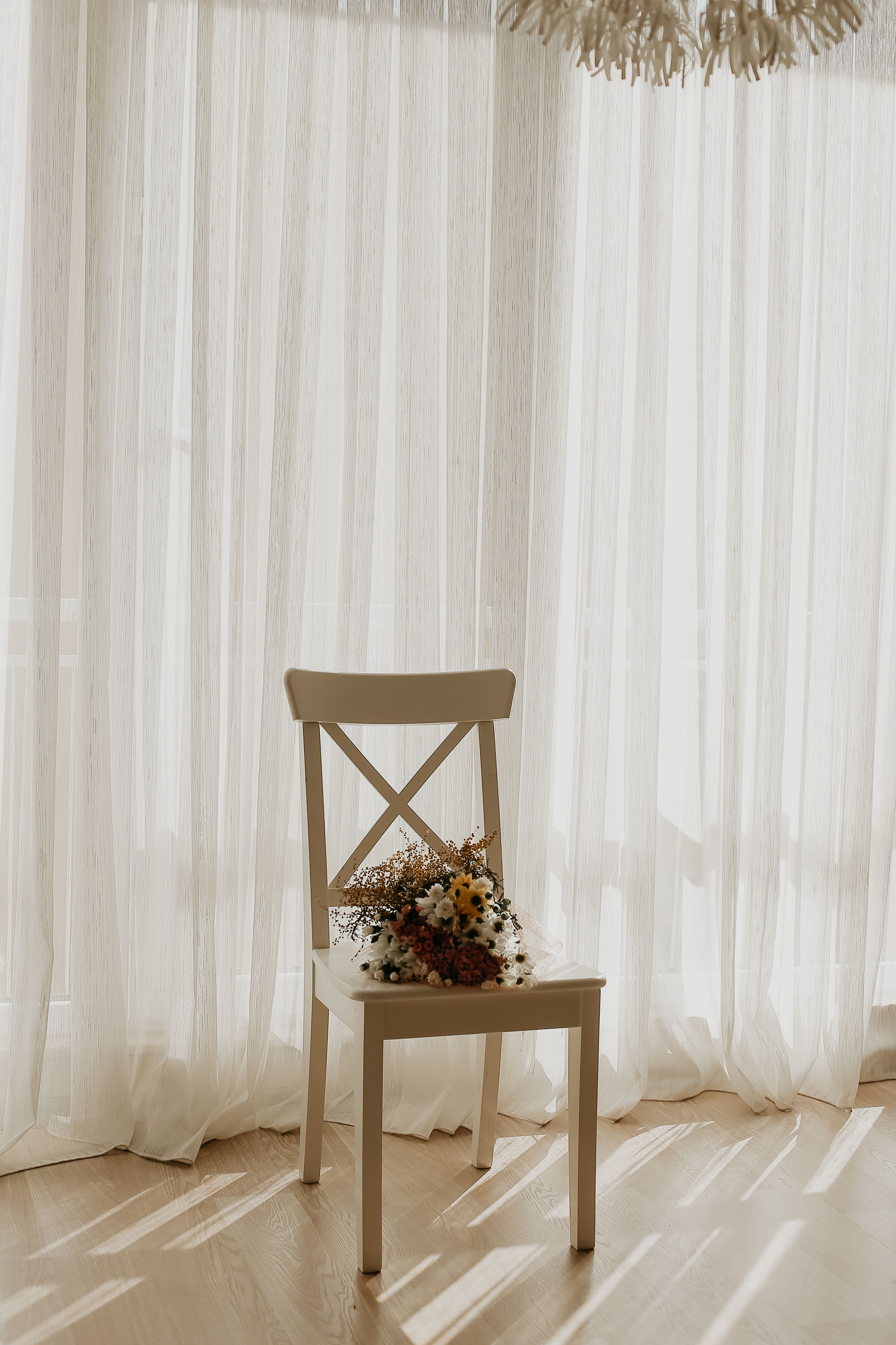 A chair with flowers sitting in front of a window · Free Stock Photo