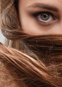 Intimate close-up of woman's eye partially obscured by her flowing hair.