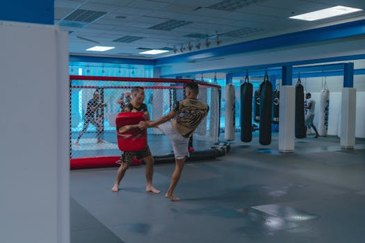 Martial artists practice MMA techniques in a well-equipped indoor gym.