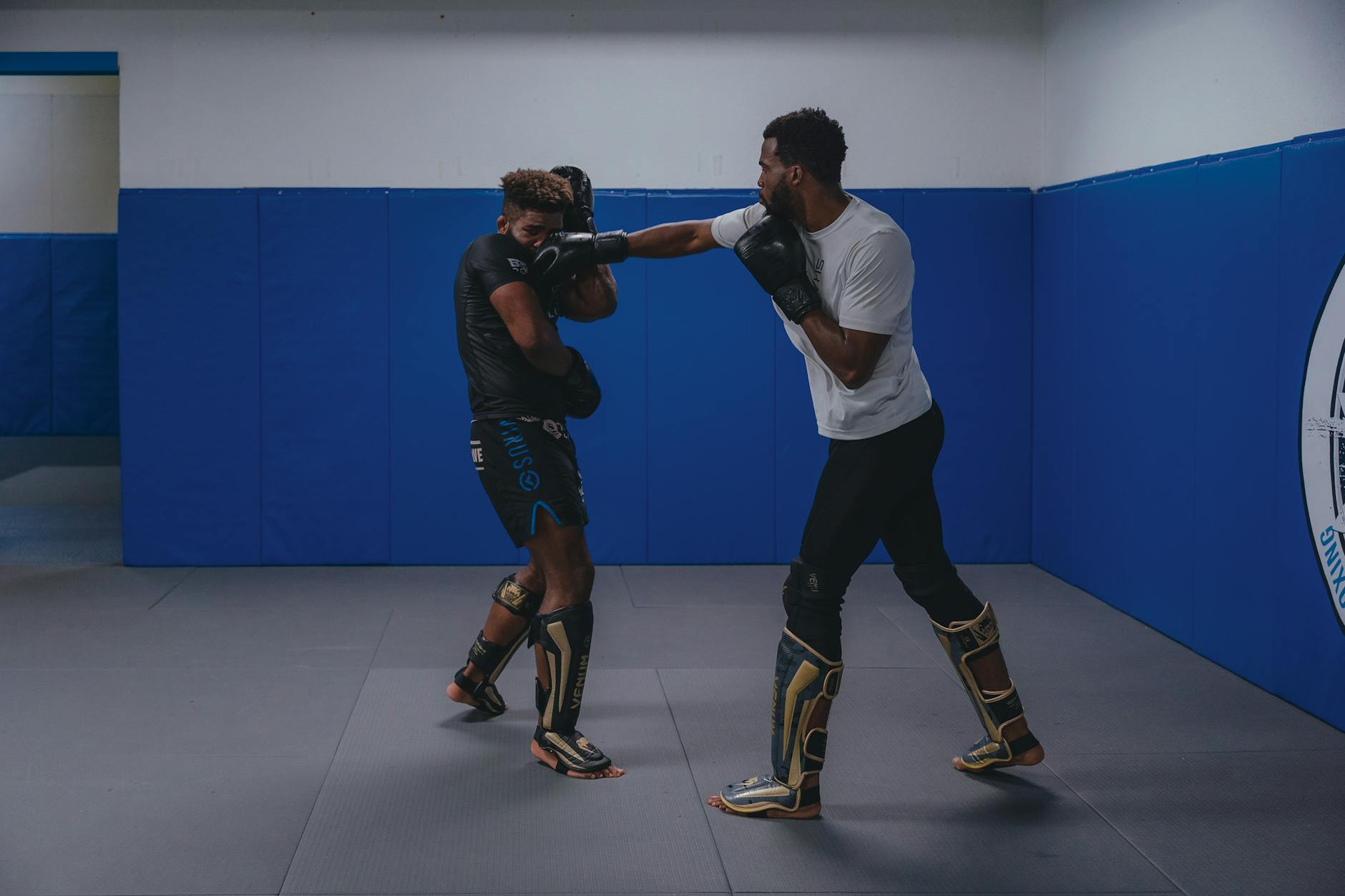 Two men engaged in sparring at a gym, practicing combat training and martial arts.
