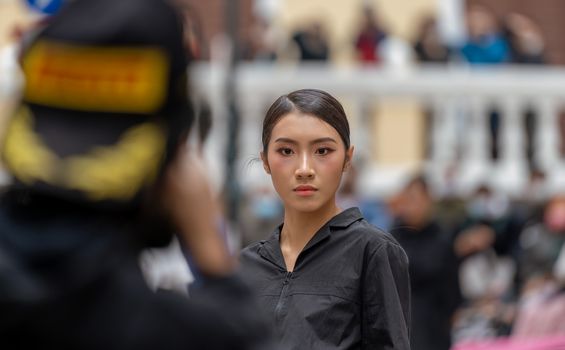 A confident Asian woman posing with poise in an urban setting, showcasing modern fashion.