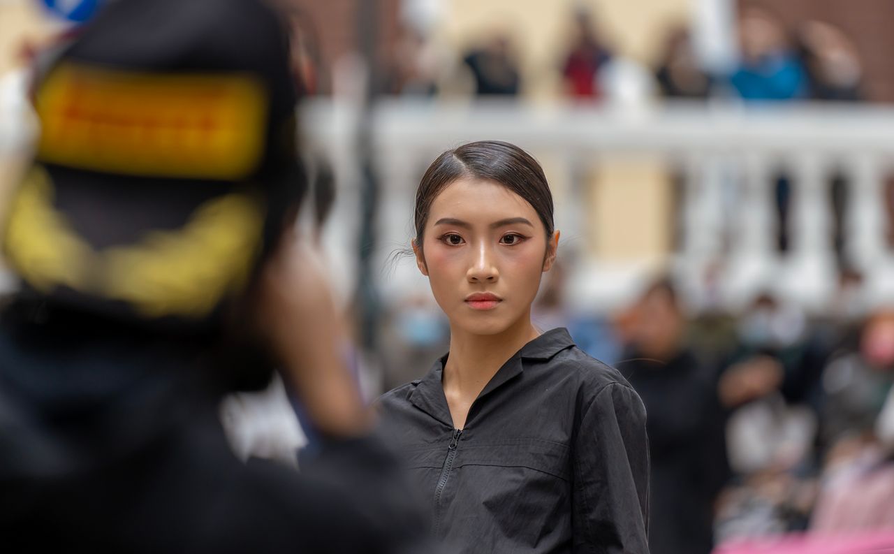 a confident asian woman posing with poise in an urban setting showcasi