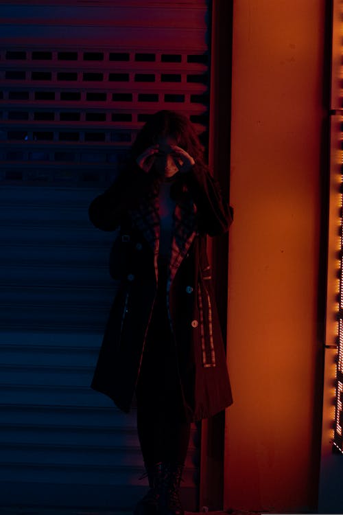 Woman in Black Coat Standing in Front of Metal Shutter