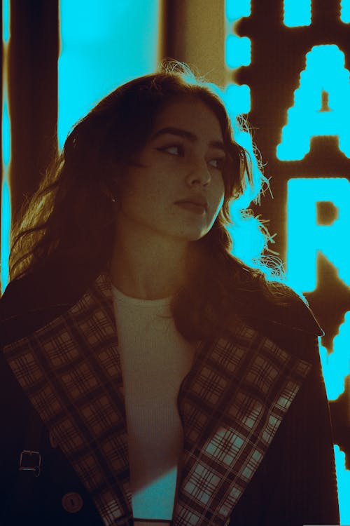 Young Woman Standing next to an LED Sign in City at Night 