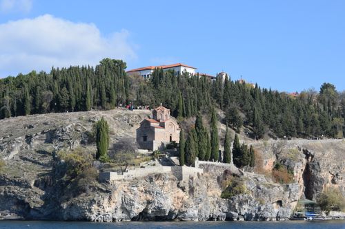 Free Beautiful view of a historic church perched on a rocky hill with cypress trees, overlooking Lake Ohrid. Stock Photo