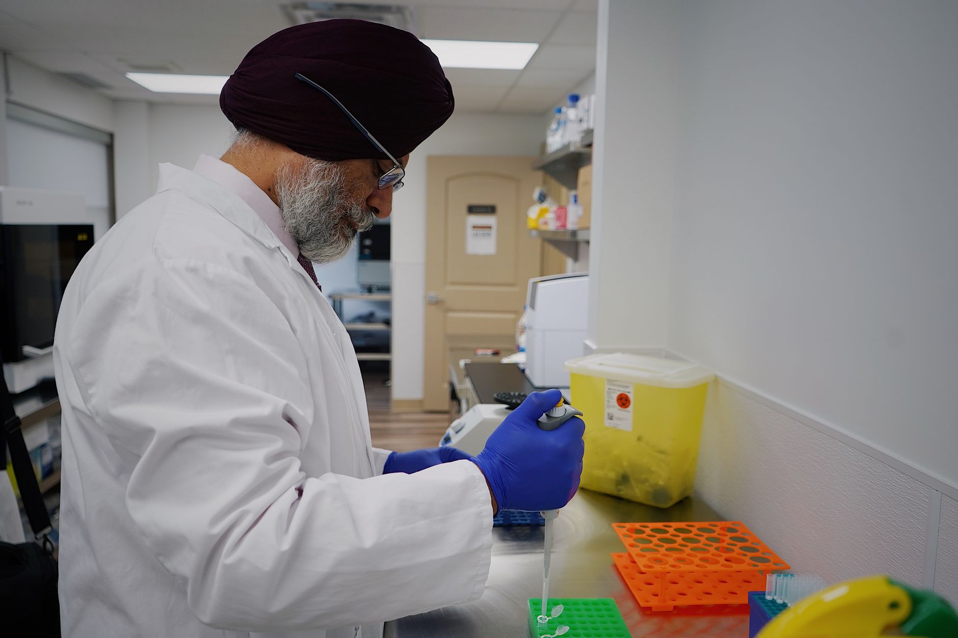 A scientist in a lab coat working with pipette inside a modern laboratory.
