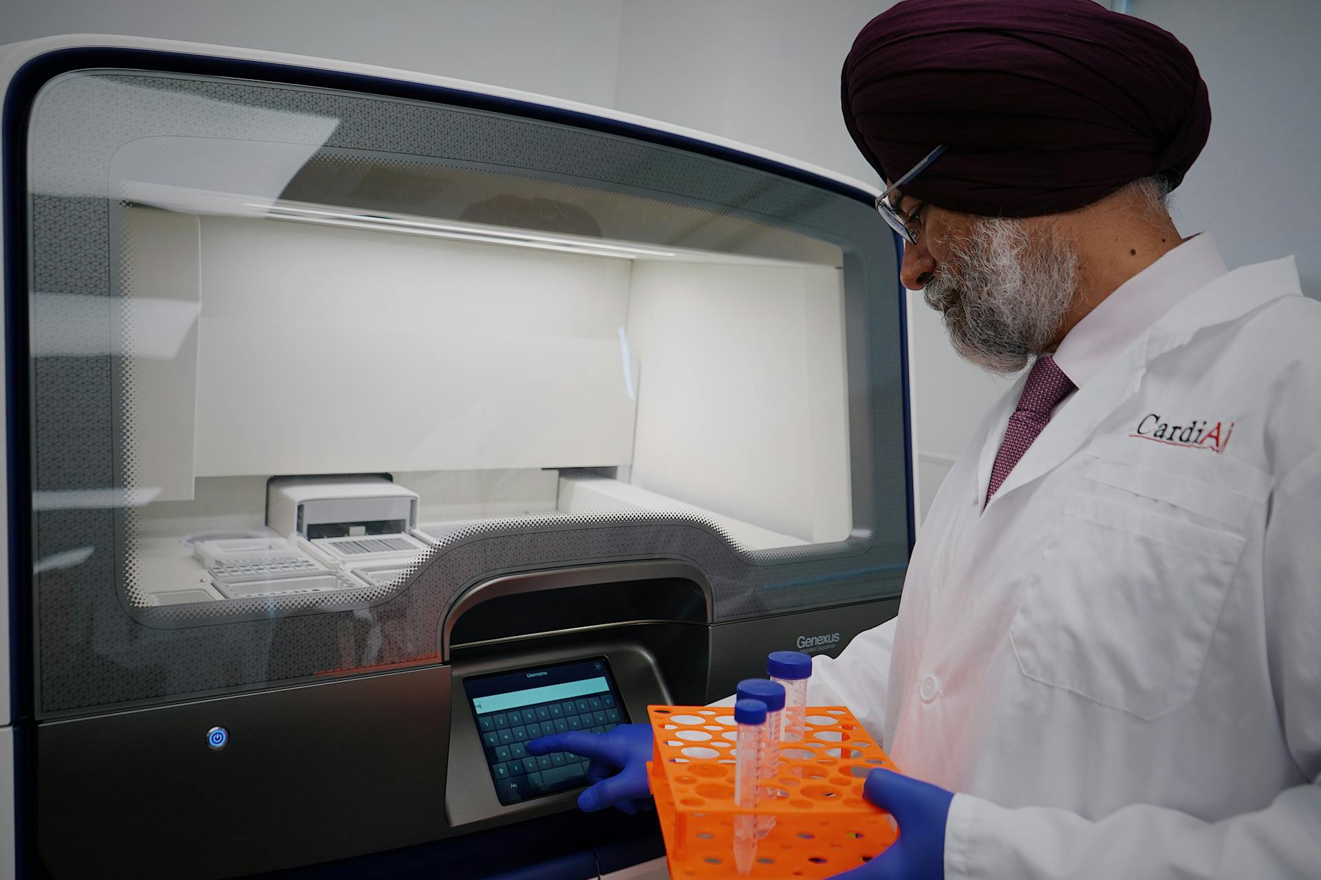 Researcher in lab analyzing samples with high-tech equipment. Wearing protective lab gear.