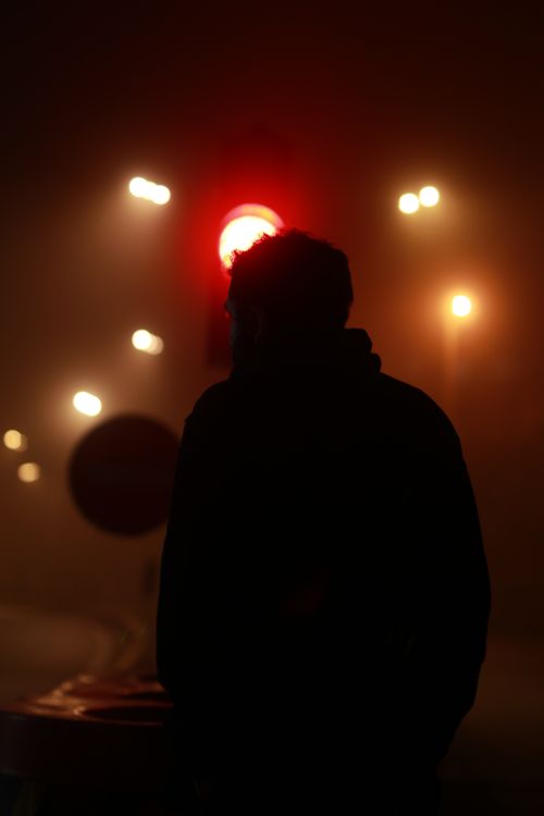 Free Silhouette of a person standing near a red traffic light in foggy night in Chalus, Iran. Stock Photo