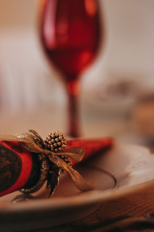 Free Close-up of a festive table setting with red accents and a decorative napkin tied with a ribbon, perfect for Christmas. Stock Photo