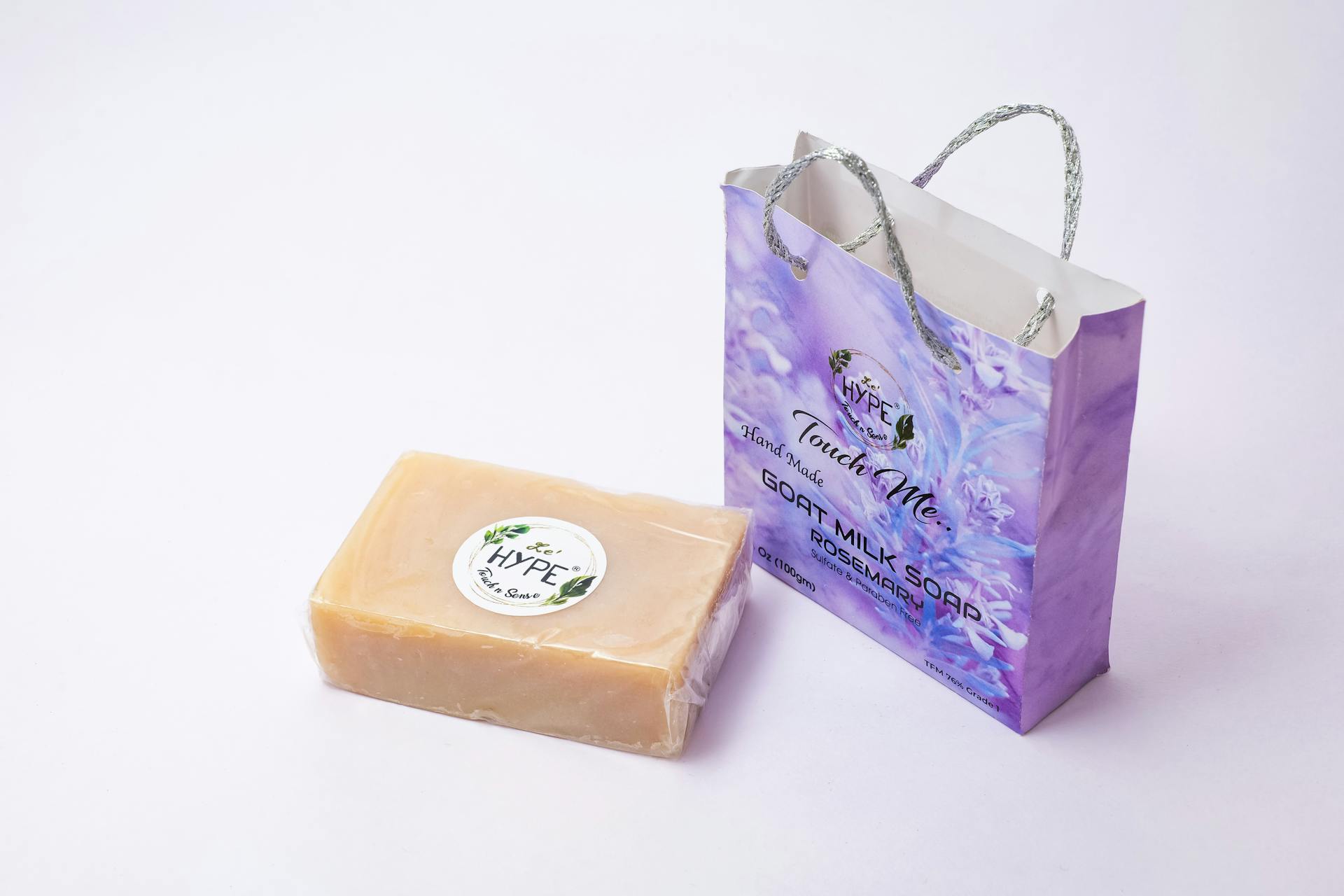 Close-up of handmade goat milk soap and packaging bag on a white background.