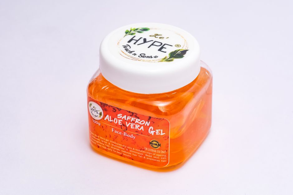 Close-up of a saffron aloe vera gel in a clear plastic container, ideal for skin care use.