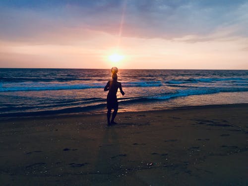 海岸でボールを遊ぶ男のシルエット