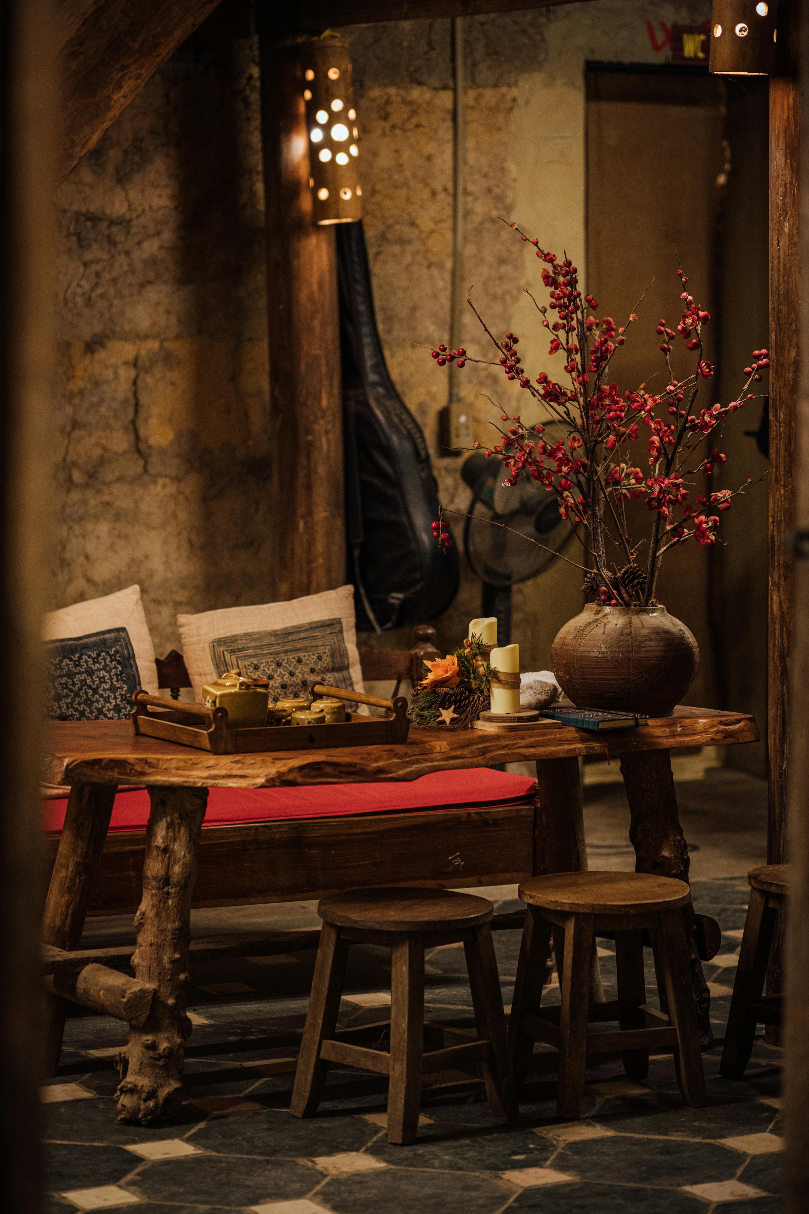 Rustic living room featuring antique furniture, ceramic vase with flowers, and warm lighting.