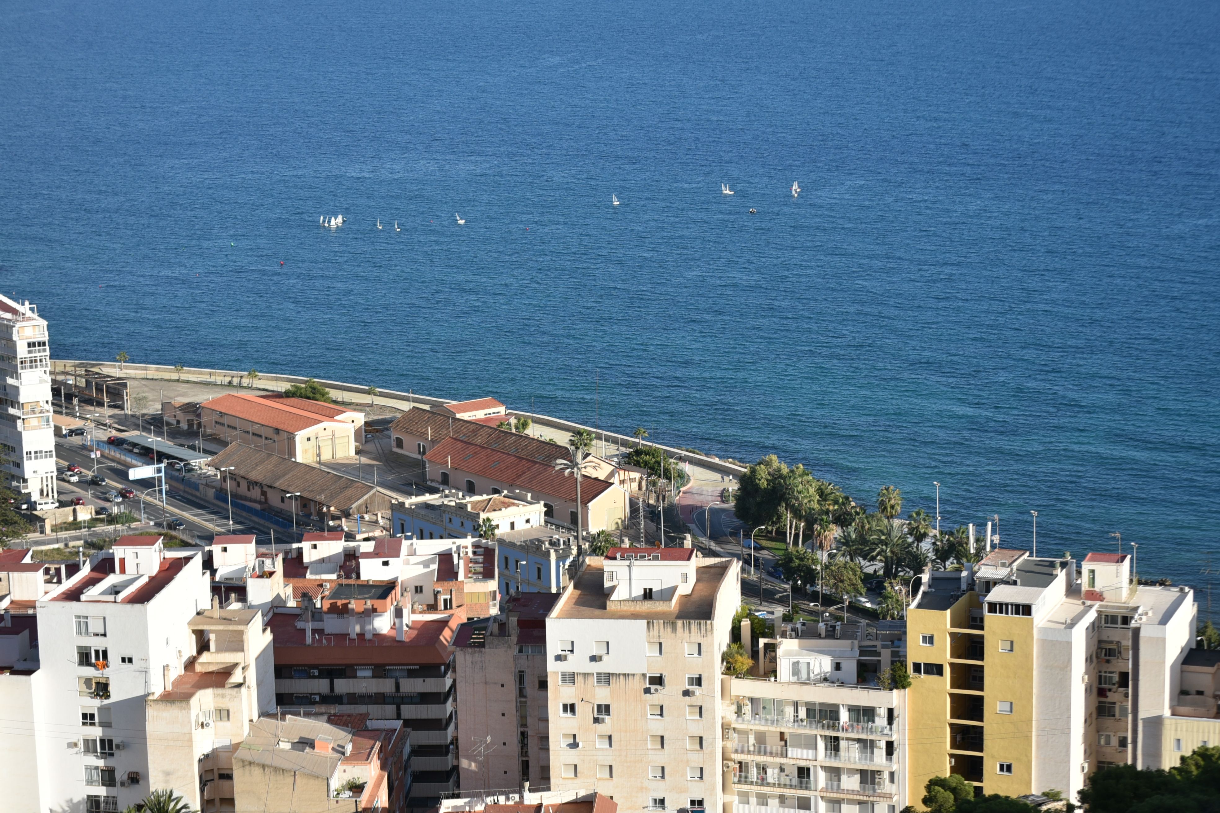 Aerial view of Alicante's waterfront cityscape with the Mediterranean sea in the background.