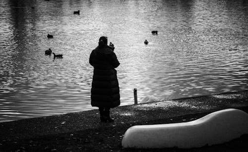 Woman Standing near Water with Ducks in Black and White