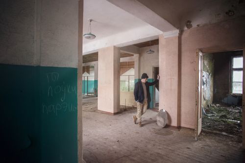 Free Man standing inside an abandoned building hallway with graffiti on walls. Stock Photo