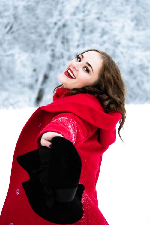 Free Smiling woman in red coat enjoying winter snow, outdoor fashion portrait. Stock Photo
