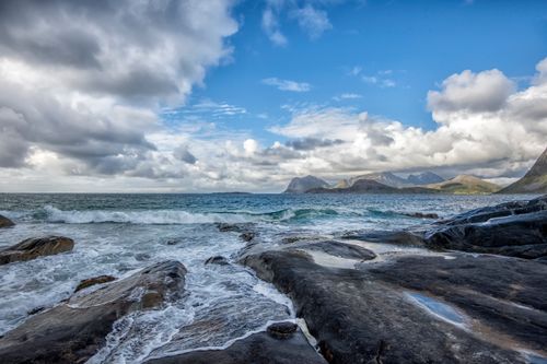 Free Serene coastal landscape of Offersøya, Norway with waves and mountain views under cloudy skies. Stock Photo