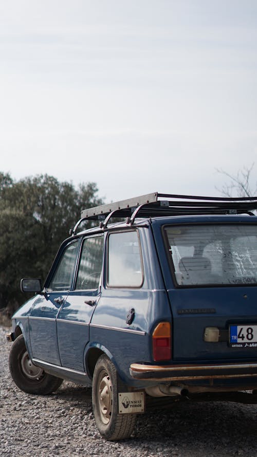 Blue Hatchback Car Driving on Rocky Road