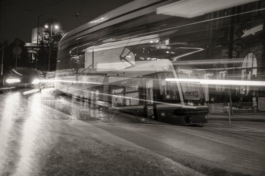 Artistic black and white long exposure of a tram in Bydgoszcz city at night.