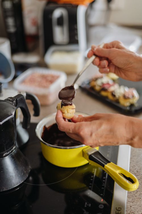 Hands frosting choux pastry in a kitchen — photo by Anete Lusina on Pexels