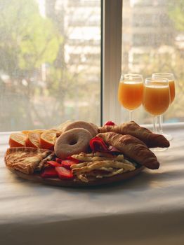 Tasty breakfast platter featuring pastries and fresh oranges by a window.