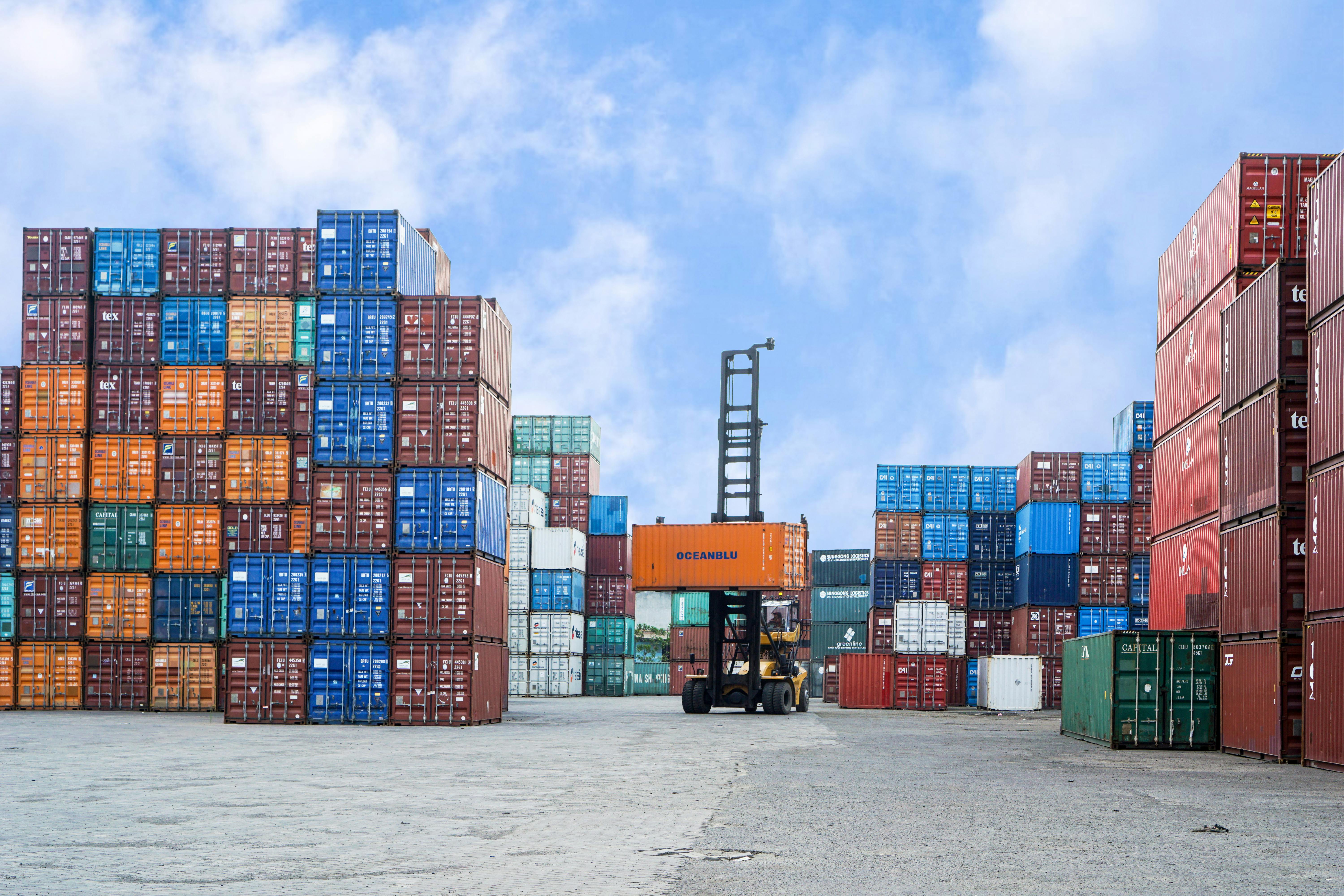 Colorful shipping containers and forklift in a busy Jakarta port under blue skies.