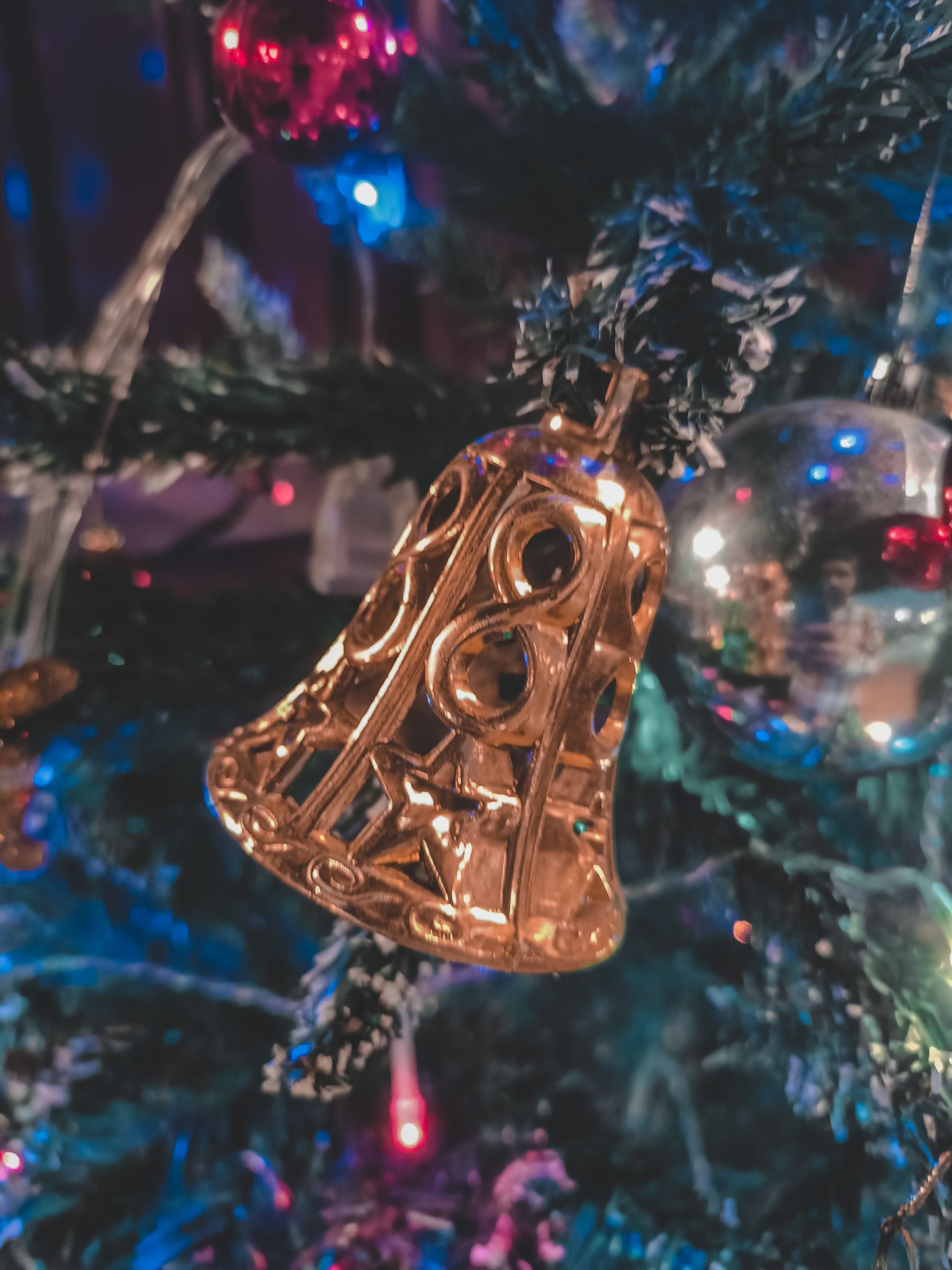Vintage bell-shaped Christmas ornament hanging among warm tree branches