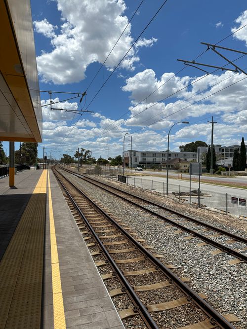 Free Sunny day view of empty railway tracks at a station platform under a bright blue sky. Stock Photo