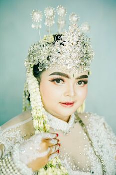 A stunning portrait of a bride wearing an elaborate and sparkling headdress, captured in a studio setting.