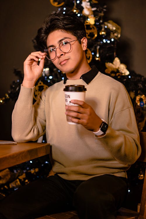 A Man in a Brown Sweater Holding a Cup of Coffee