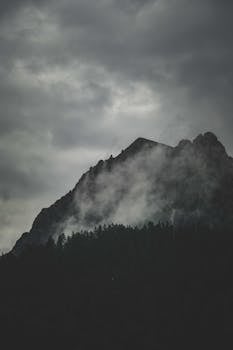Dramatic misty mountain with dark clouds, perfect for moody mobile wallpapers.