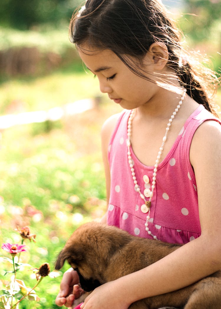 A Young Girl In Pink Tank Top Petting Her Dog